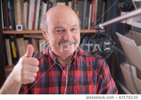Senior retired man blogger looking at camera recording vlog, smiling old elder grandfather showing thumb up 83578210