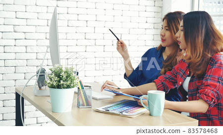 Happiness two women working together confident team meeting in office desk. Team business partners working with computer laptop startup company. Asian colleague friendship at work with smiling face. 83578468