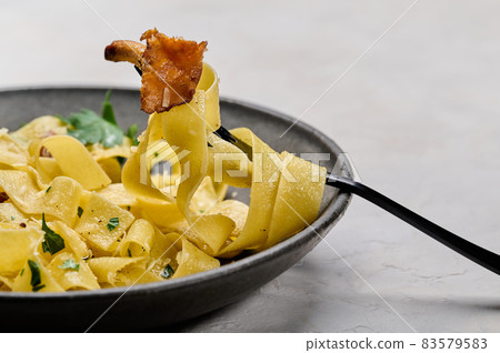 Macro selective focus fork with traditional pasta pappardelle with mushrooms chanterelles Macro selective focus fork with traditional pasta pappardelle with mushrooms chanterelles 83579583