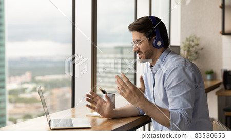 Happy young man in headphones holding video call conversation. 83580653