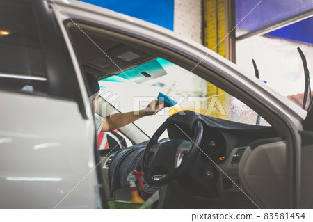 Man specialist installing tinting film on car window. Man specialist installing tinting film on car window. 83581454