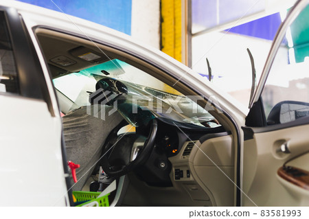 Male specialist applying window tinting film on the car. Male specialist applying window tinting film on the car. 83581993