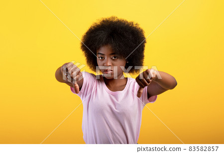 Dislike. Unhappy black lady showing thumb down gesture, displeased young woman expressing disapproval Dislike. Unhappy black lady showing thumb down gesture, displeased young woman expressing disapproval 83582857