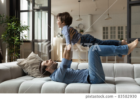 Smiling young father playing with little child son. 83582930