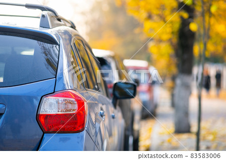 Cars parked in a row on a city street side on bright autumn day. 83583006