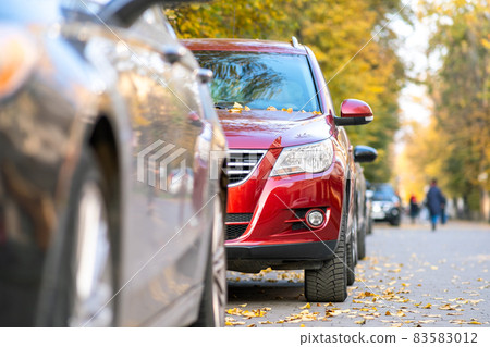 Cars parked in a row on a city street side on bright autumn day. Cars parked in a row on a city street side on bright autumn day. 83583012