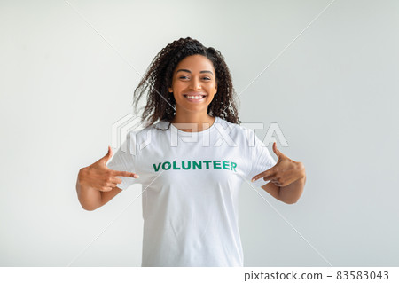 Young african american woman showing volunteer t-shirt and smiling, pointing herself with fingers proud and happy 83583043
