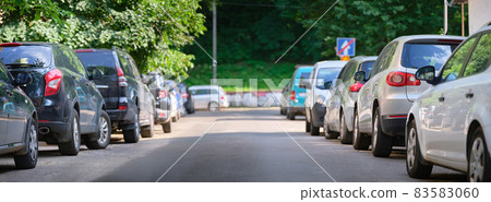 City traffic with cars parked in line on street side. 83583060