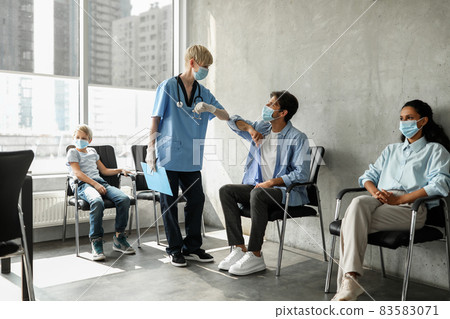 Female doctor greeting young man patient with elbow bump Female doctor greeting young man patient with elbow bump 83583071