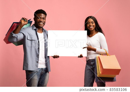Happy black couple shopaholics holding empty board 83583106
