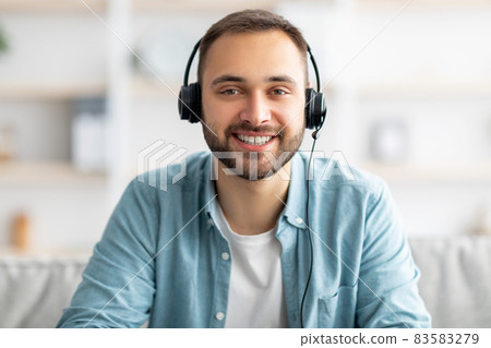 Cheerful young Caucasian guy in headphones having online video call, participating in conference or remote meeting Cheerful young Caucasian guy in headphones having online video call, participating in conference or remote meeting 83583279