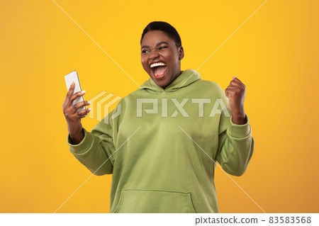 Emotional African Woman Holding Smartphone Gesturing Yes On Yellow Background 83583568