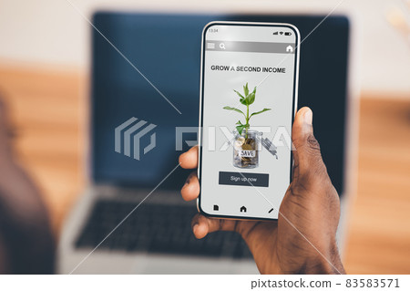 Hands of young black businessman hold smartphone with website, grow second income on screen, financial savings Hands of young black businessman hold smartphone with website, grow second income on screen, financial savings 83583571