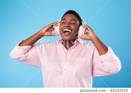 African American Female Listening Music With Eyes Closed, Blue Background African American Female Listening Music With Eyes Closed, Blue Background 83583576