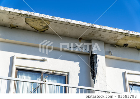 The outer wall of a building that has deteriorated and the reinforcing bars are exposed 83583798