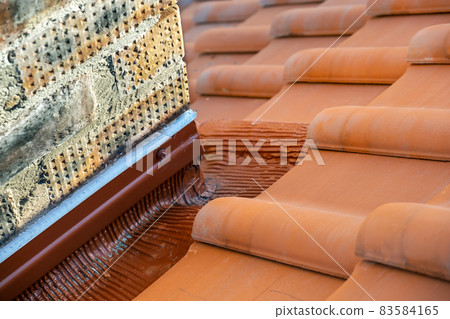 Rows of yellow ceramic roofing tiles covering residential building roof near brick chimney. Rows of yellow ceramic roofing tiles covering residential building roof near brick chimney. 83584165