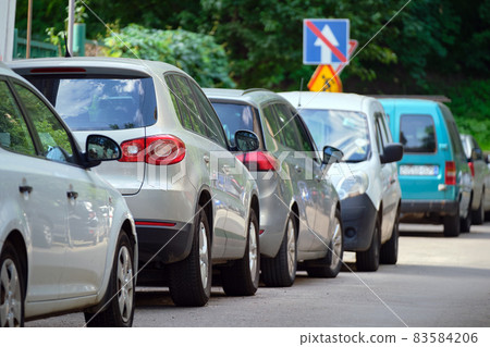 City traffic with cars parked in line on street side. 83584206