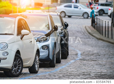 City traffic with cars parked in line on street side. 83584765