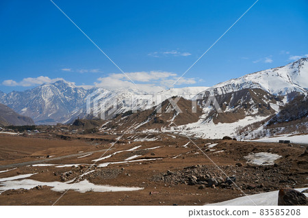 In a mountain valley, a breathtaking landscape of giant covered mountains in the background 83585208