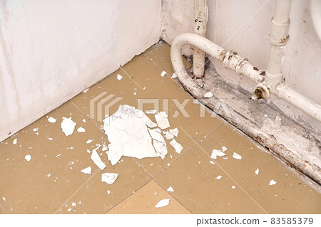 The interior is an old house in need of renovation. The crumbling white plaster from the wall lies on the floor, near the old radiator The interior is an old house in need of renovation. The crumbling white plaster from the wall lies on the floor, near the old radiator 83585379