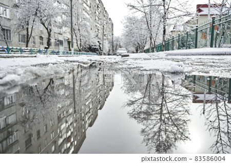 Reflection on the puddle of winter snow covered city scenery 83586004
