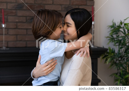 Happy Asian mixed race mom holding son boy in arms 83586317