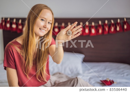 Woman making Christmas advent calendar. Pouches on a rope 83586440