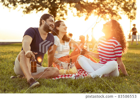 Three friends sitting on the grass in the park 83586553