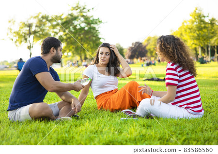 Three friends sitting on the grass in the park 83586560