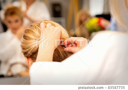 Hair stylist's hands doing professional hairstyling of female long hair in a beauty salon. Hair stylist's hands doing professional hairstyling of female long hair in a beauty salon. 83587735