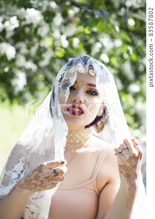 young pretty indian girl in jewelry and veil posing cheerful happy smiling in green park, lifestyle people concept 83587802