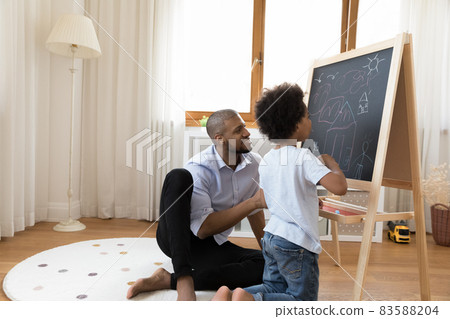 Happy little african american boy drawing with father. Happy little african american boy drawing with father. 83588204