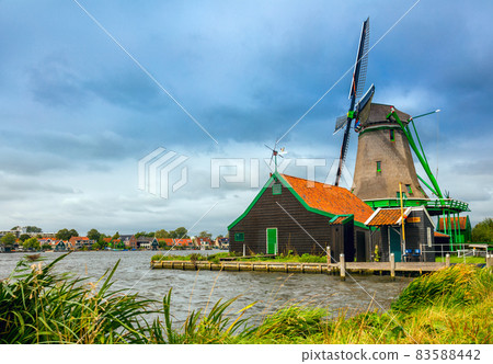 Dutch Landscape - village with a windmill and a house. Agricultural Historical Landscape. Tourism. Popular Holland, Netherlands, Europe. Dutch Landscape - village with a windmill and a house. Agricultural Historical Landscape. Tourism. Popular Holland, Netherlands, Europe. 83588442