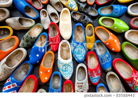 Traditions of Holland Background - A lot of colorful old clomps against the background of a wooden wall. Popular souvenirs. Traditions of Holland Background - A lot of colorful old clomps against the background of a wooden wall. Popular souvenirs. 83588443
