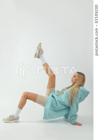 Young pretty woman wearing turquoise hoodie and gray cycling shorts on white background Young pretty woman wearing turquoise hoodie and gray cycling shorts on white background 83589280