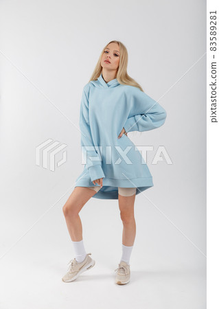 Young pretty woman wearing blue hoodie and gray cycling shorts on white background. Casual women sport look Young pretty woman wearing blue hoodie and gray cycling shorts on white background. Casual women sport look 83589281