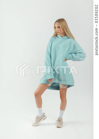 Young pretty woman wearing turquoise hoodie and gray cycling shorts on white background Young pretty woman wearing turquoise hoodie and gray cycling shorts on white background 83589282