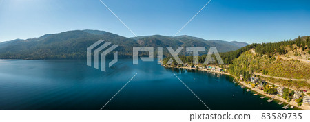 Aerial panoramic view of a residential homes by a lake and mountains. Aerial panoramic view of a residential homes by a lake and mountains. 83589735