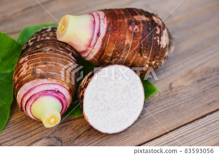 Taro root with half slice on taro leaf and wooden background, Fresh raw organic taro root ready to cook 83593056