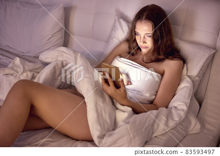 Woman is chatting with friends in bed using phone before sleeping. Woman is chatting with friends in bed using phone before sleeping. 83593497