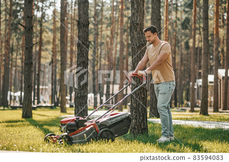 Man walking on grass with lawn mower 83594083
