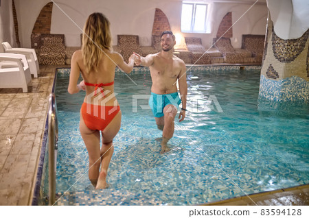 A couple in a pool holding hands and looking at each other 83594128