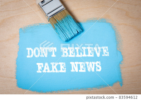 Don't believe fake news. Brush with blue paint on a wooden background 83594612