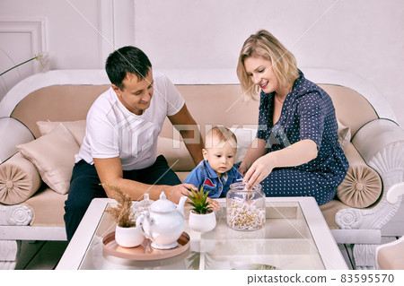 Toddler with parents sit on couch in lounge. Toddler with parents sit on couch in lounge. 83595570
