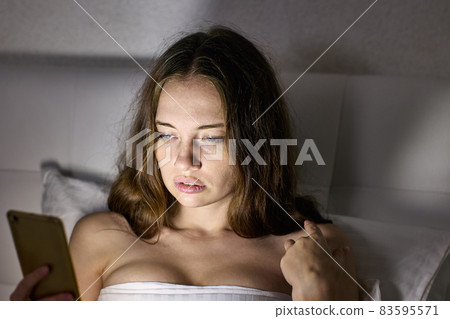 Light from screen of smartphone on woman face in bed. Light from screen of smartphone on woman face in bed. 83595571
