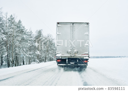 Snowy road in winter forest with moving car Snowy road in winter forest with moving car 83598111