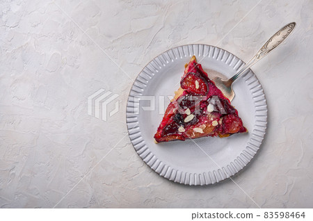 Piece of plum pie on a light plate with a shoulder blade Piece of plum pie on a light plate with a shoulder blade 83598464