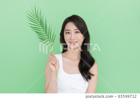 beauty concept, beautiful Korean Asian woman with green leaves, mint color background beauty concept, beautiful Korean Asian woman with green leaves, mint color background 83599712