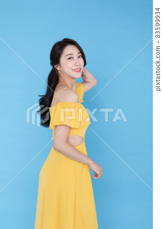 side view of smiling beautiful Korean Asian woman in summer yellow dress, skyblue background 83599934