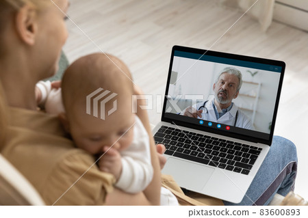 Mother holding baby, using laptop, making video call to pediatrician 83600893